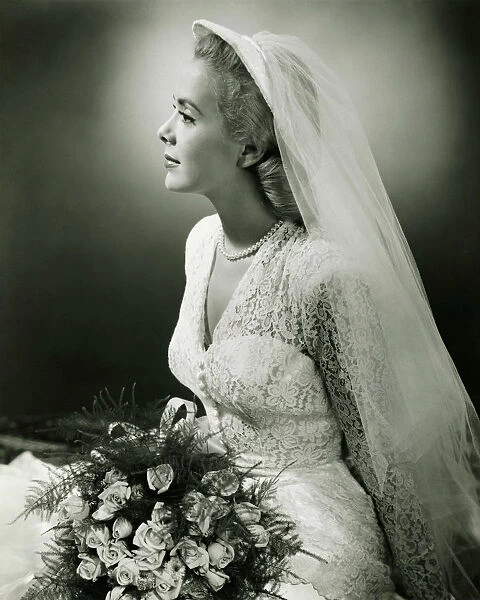 Bride with bouquet posing in studio, (B&W), portrait
