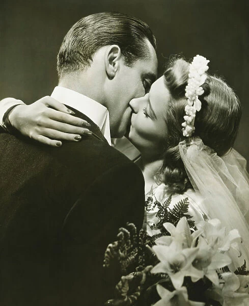 Bride and Groom kissing in studio, (B&W)