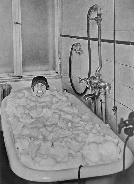 Bubble Bath. A woman in a bathtub filled with suds produced by a chemically enhanced soap