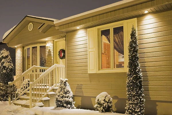 Bungalow style residential home illuminated in winter at dusk with Christmas decorations, Quebec, Canada