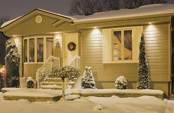 Bungalow style residential home illuminated in winter at dusk with Christmas decorations, Quebec, Canada