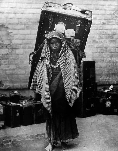 Burdened. circa 1930: A poor Kashmiri woman carrying a trunk as large as