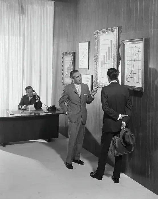 Framed Print : Two businessman discussing at bar chart while another man using telephone in background Framed Print : Two businessman discussing at bar chart while another man using telephone in background