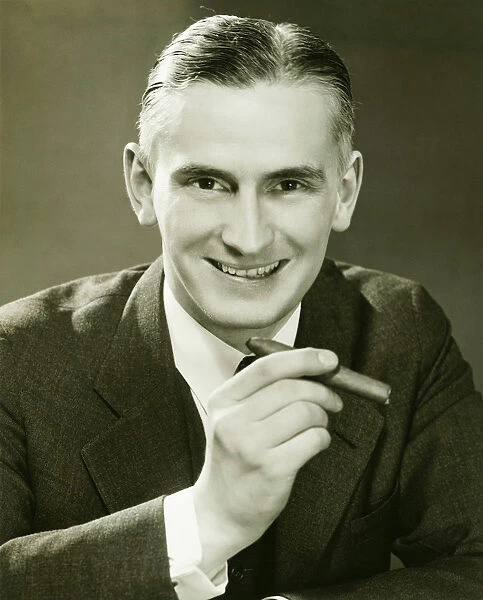 Businessman holding cigar, (B&W), portrait
