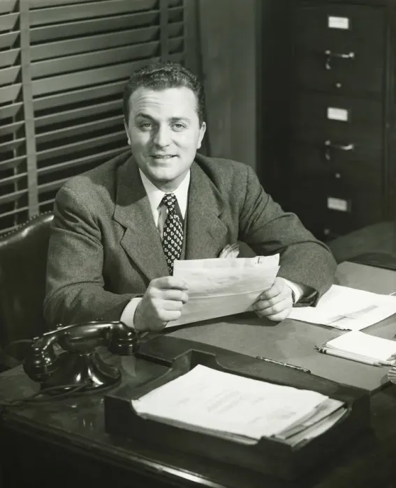 Framed Print : Businessman holding documents, sitting at office, (B&W) Framed Print : Businessman holding documents, sitting at office, (B&W)