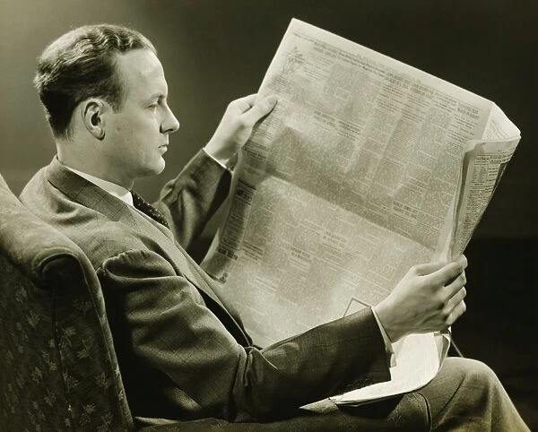 Businessman reading newspaper, (B&W)