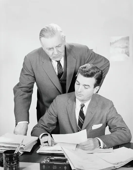 Framed Print : Businessman sitting at desk, with boss looking over shoulder, reviewing paperwork Framed Print : Businessman sitting at desk, with boss looking over shoulder, reviewing paperwork
