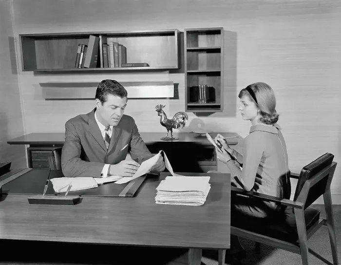 Framed Print : Businessman sitting at desk reading papers, secretary taking notes Framed Print : Businessman sitting at desk reading papers, secretary taking notes