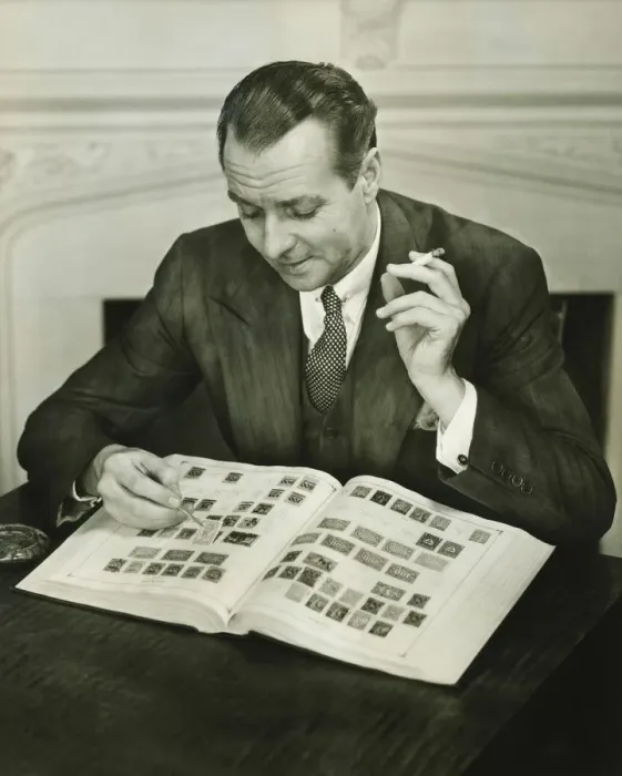 Framed Print : Businessman sitting at small table, with stamp album, (B&W) Framed Print : Businessman sitting at small table, with stamp album, (B&W)