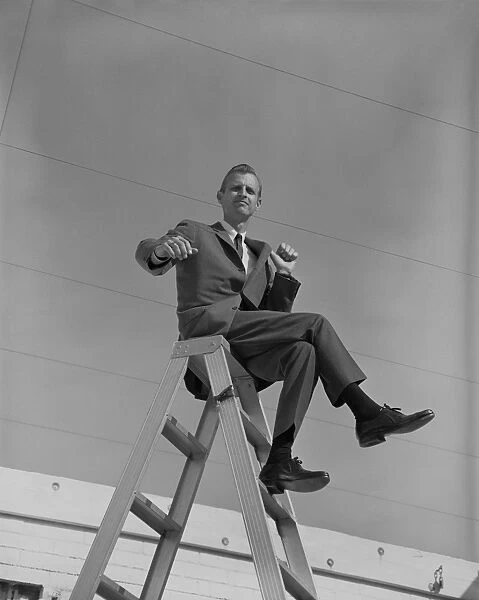 Businessman sitting on top of step ladder, portrait