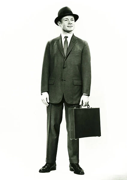 Businessman standing in studio, (B&W), portrait