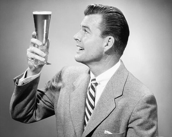 Businessman in full suit in studio holding glass of beer, (B&W)