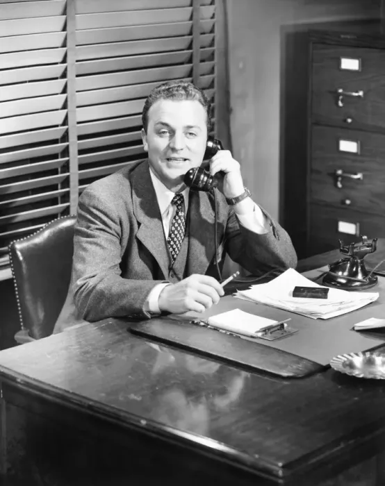 Framed Print : Businessman talking on phone at desk (B&W) Framed Print : Businessman talking on phone at desk (B&W)