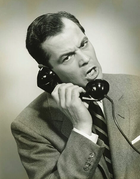 Businessman using phone in studio, (B&W), close-up