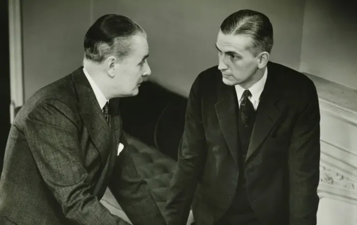 Framed Print : Two businessmen leaning on desk, talking, (B&W) Framed Print : Two businessmen leaning on desk, talking, (B&W)