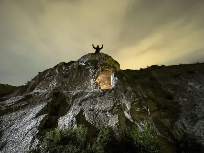 Framed Print : Cave excavated in the rock, on the top of a mountain with a man raises with the arms raised in the night Framed Print : Cave excavated in the rock, on the top of a mountain with a man raises with the arms raised in the night