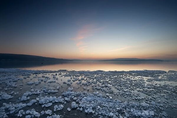 Chunks of ice lying on icy surface on the shore of Reichenau Island after sunset, Baden-Wuerttemberg, Germany, Europe