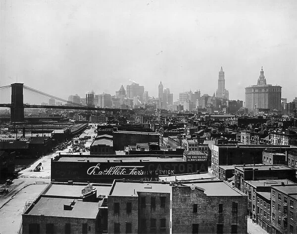 circa 1920: View of the buildings at South Street Seaport and the Brooklyn Bridge