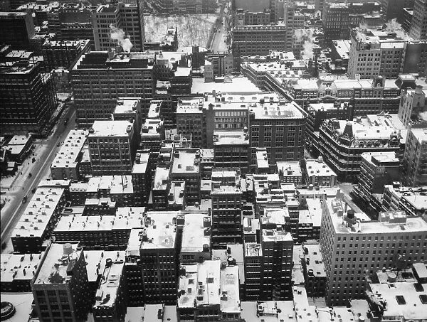 circa 1925: High angle view of snow-covered rooftops of apartment buildings, with
