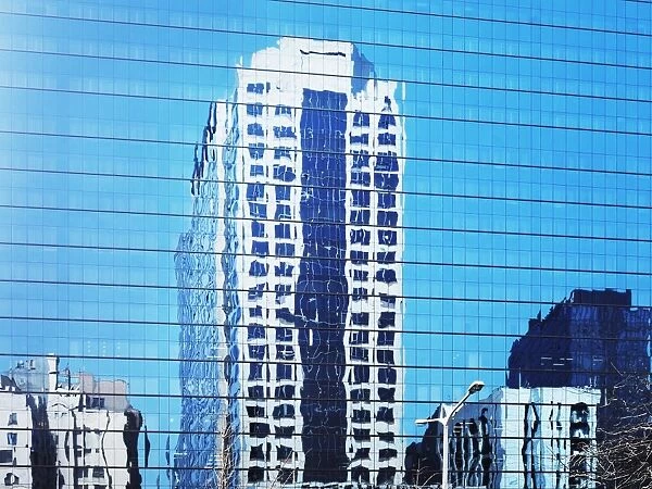 Cityscape reflected in glass facade of building