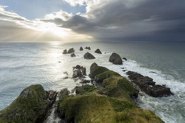 Cliffs rising from the Pacific with a rising sun, at Nugget Point, Nugget Point, Ahuriri Flat, Otago Region, New Zealand