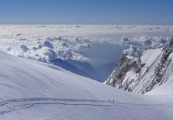 Two climbers above the clouds on Monte Rosa, Alps, Valle dAosta, Italy
