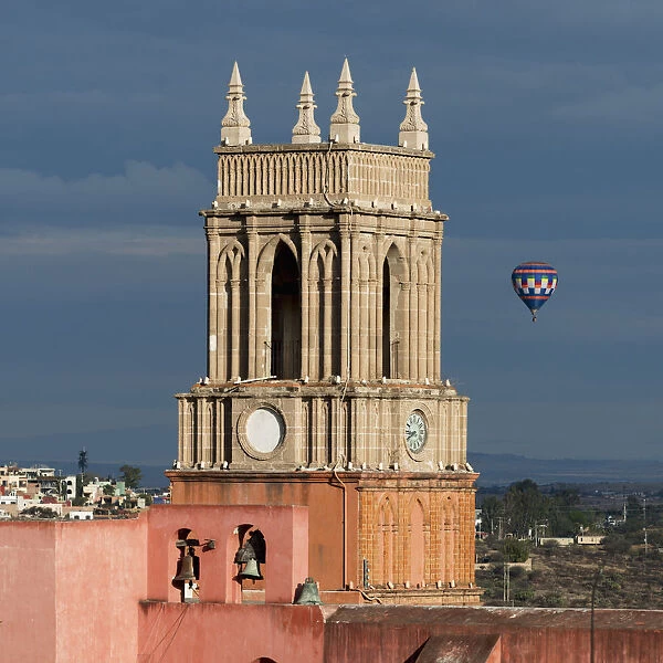 Clock tower and bells of the parish church with a hot air balloon flight in the distance
