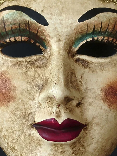 Closeup of a paper mache Venetian mask depicting a beautiful womans face, eyes, nose and mouth