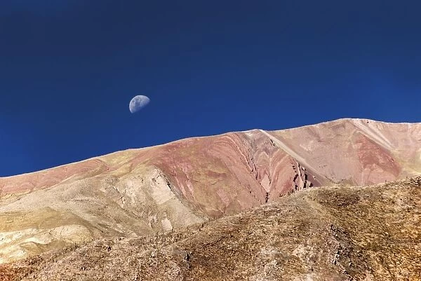 colorful hills with the moon in the blue sky