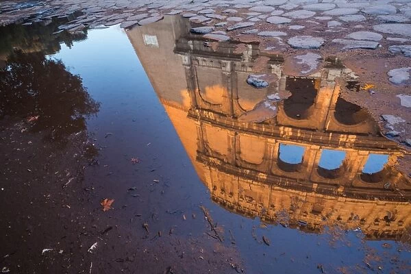 The Colosseum reflected in a puddle at sunrise in Rome, Italy