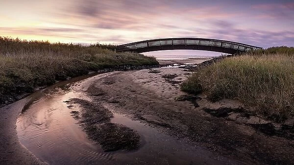 Colourful sunrise behind the Luegenbruecke on the mudflats in the east of the North Frisian island of Sylt, Germany
