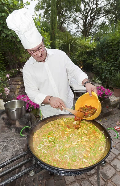 Cook preparing a paella, a Spanish rice dish, adding peppers, series, no. 2