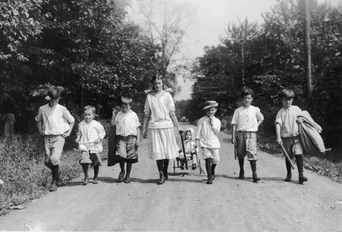 Framed Print : Country Walk; group of seven children walking in a row, and an eighth being pulled in a cart