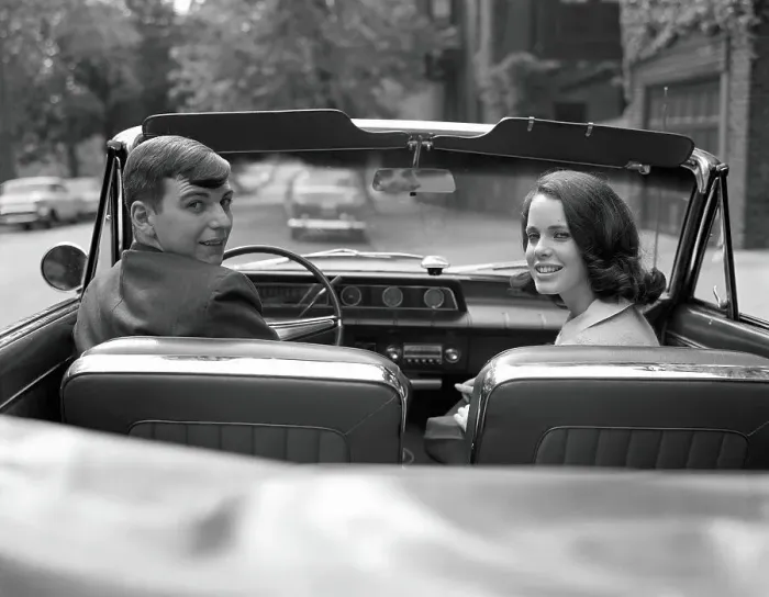 Framed Print : Couple in convertible, smiling, looking over shoulders, portrait Framed Print : Couple in convertible, smiling, looking over shoulders, portrait