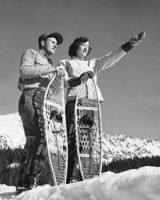 Framed Print : Couple holding snowshoes, woman pointing Framed Print : Couple holding snowshoes, woman pointing