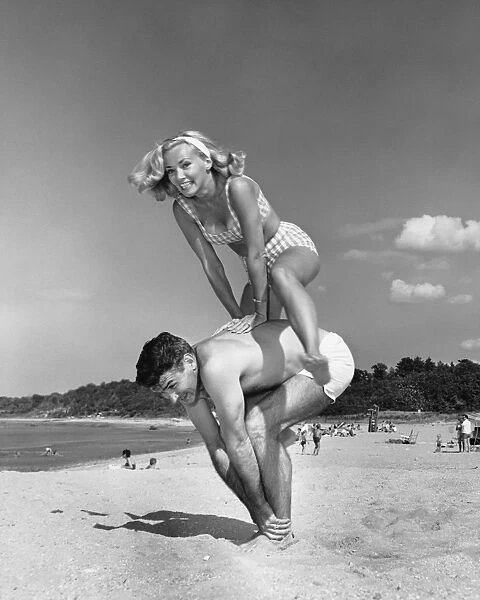 Couple playing leapfrog on beach