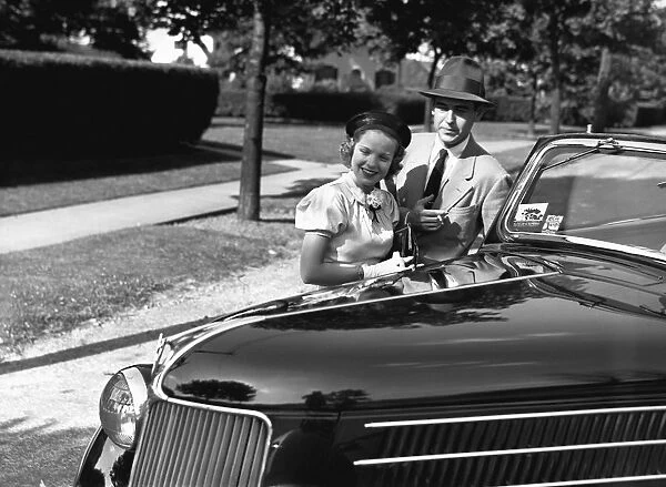 Couple posing at open top car, (B&W), portrait