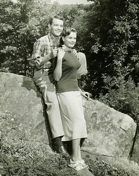 Couple sitting on boulder in park, (B&W)