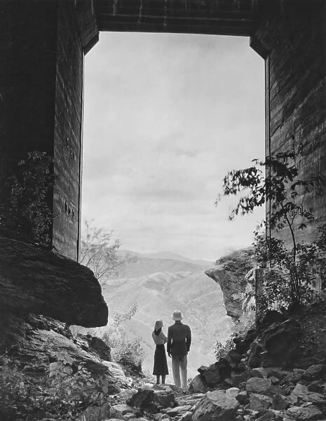Couple standing in gate, looking at view, (B&W)