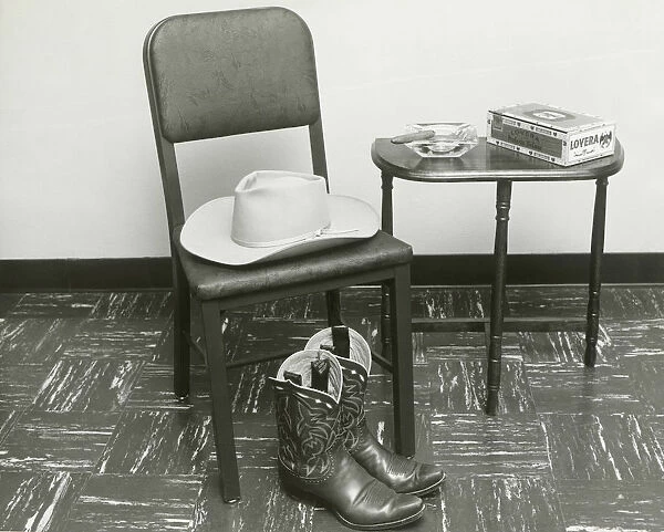 Cowboy hat and boots on chair beside table