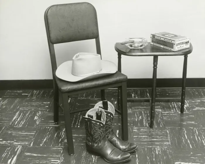 Framed Print : Cowboy hat and boots on chair beside table Framed Print : Cowboy hat and boots on chair beside table