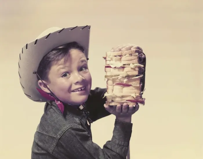 Framed Print : Cowboy holding sandwich, smiling, portrait