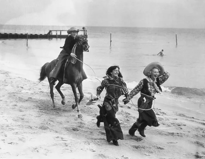 Framed Print : Cowboy on horse catching laughing women on beach