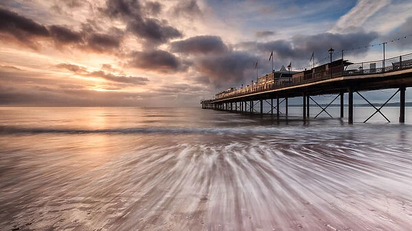 Dawn Pier. Image shows a pier at sunrise with the tide in motion