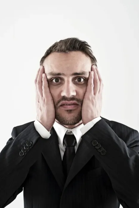 Framed Print : Desperate young man wearing a suit holding his hands to his face, worried Framed Print : Desperate young man wearing a suit holding his hands to his face, worried