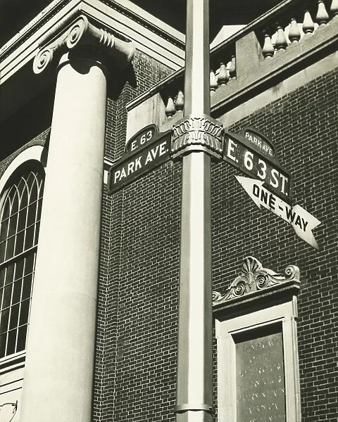 Directional sign and part of building, low angle view (B&W)