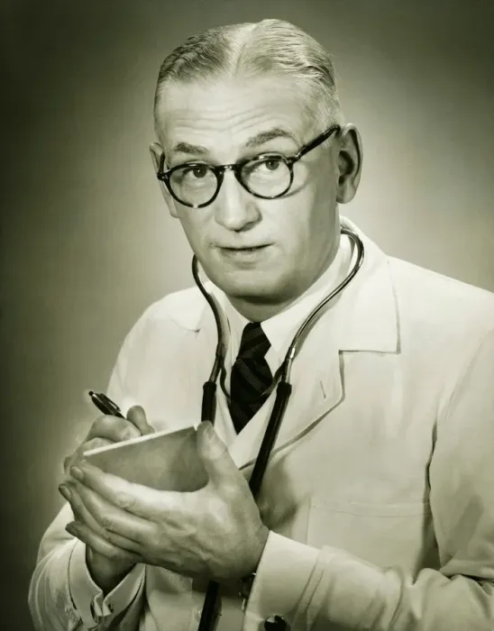 Framed Print : Doctor holding note pad posing in studio, (B&W), portrait Framed Print : Doctor holding note pad posing in studio, (B&W), portrait