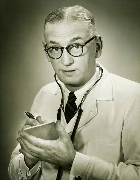 Doctor holding note pad posing in studio, (B&W), portrait