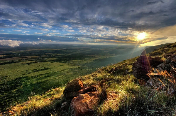 Dramatic Sunset from the edge of a cliff over the Magaliesberg Mountain Range looking towards the flat agricultural North-West Province of South Africa. Magaliesberg Mountains, North-West Province, South Africa