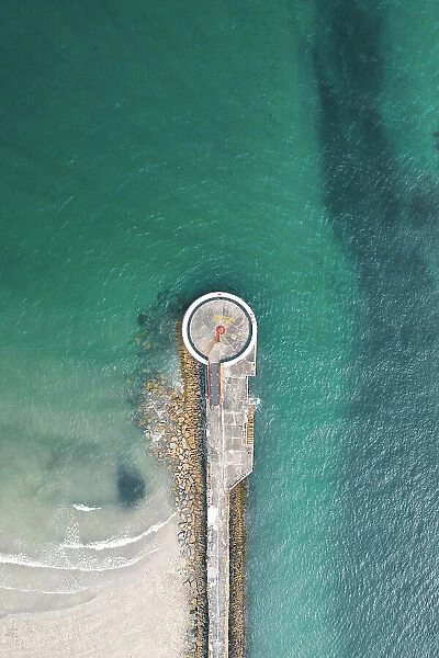 Drone shot above a small lighthouse on a pier, Looe, Cornwall, United Kingdom
